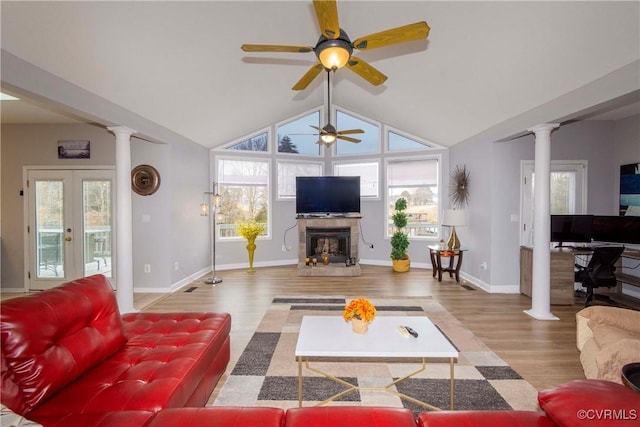 living area featuring vaulted ceiling, wood finished floors, a ceiling fan, and ornate columns