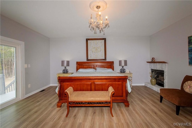 bedroom featuring access to outside, a notable chandelier, baseboards, and light wood-type flooring