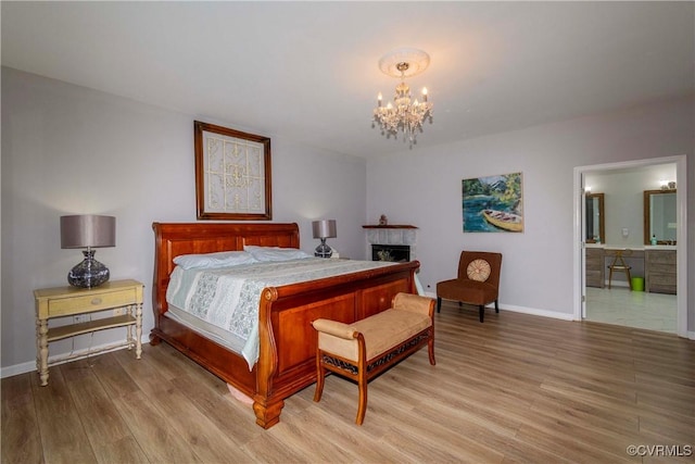 bedroom featuring an inviting chandelier, light wood-style flooring, baseboards, and a tile fireplace