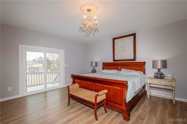 bedroom with baseboards, wood finished floors, an inviting chandelier, and access to outside