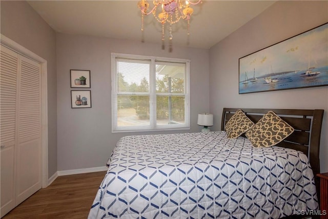 bedroom featuring wood finished floors, baseboards, a closet, and a chandelier