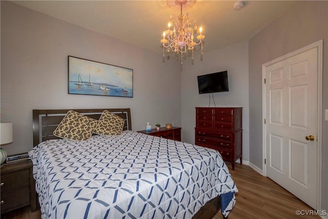 bedroom featuring a notable chandelier, baseboards, and wood finished floors