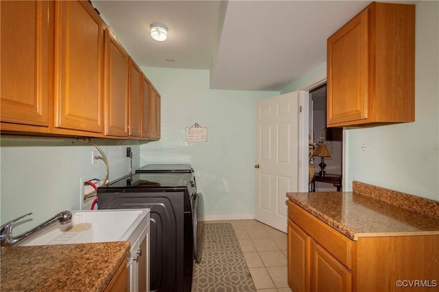 laundry room featuring washing machine and clothes dryer, light tile patterned floors, cabinet space, and baseboards