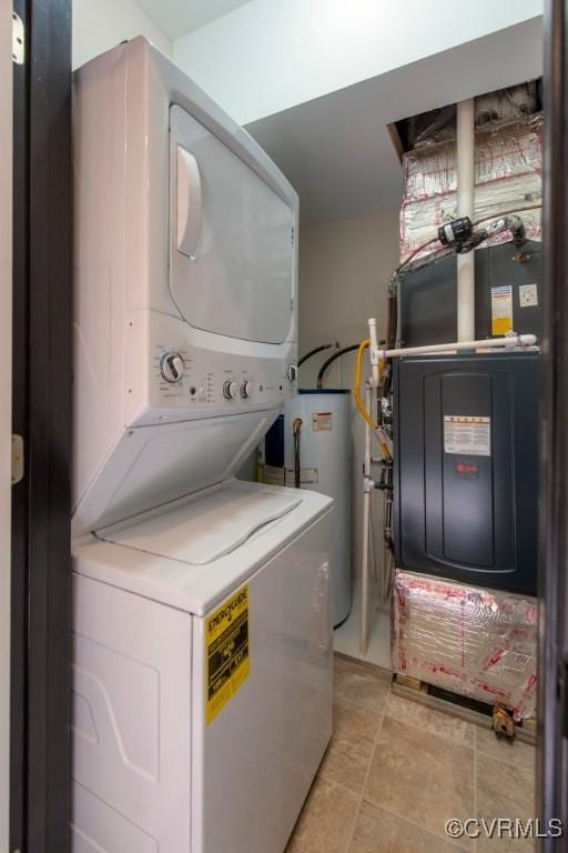 clothes washing area with laundry area, stacked washer and dryer, light tile patterned floors, and water heater