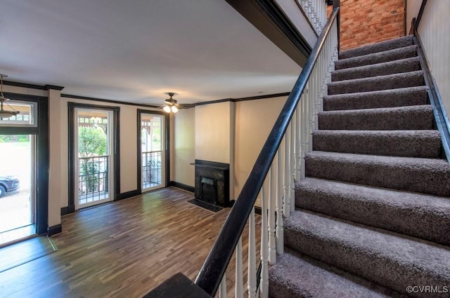 stairs with ceiling fan, baseboards, wood finished floors, and ornamental molding