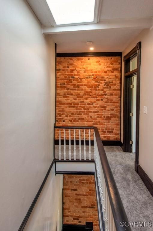 stairs featuring carpet flooring, brick wall, and baseboards