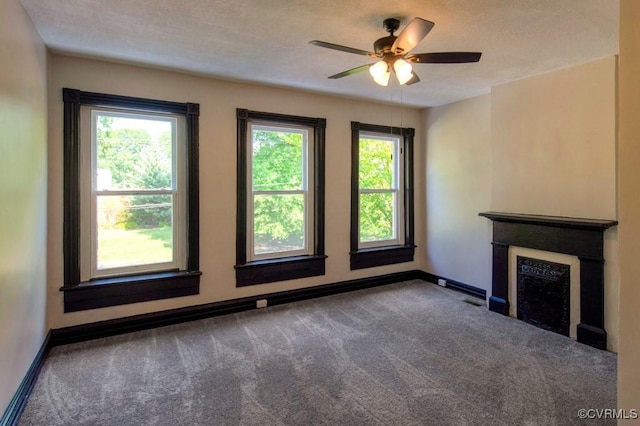 unfurnished living room featuring plenty of natural light, a fireplace, baseboards, and carpet