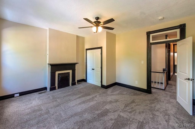 unfurnished living room featuring carpet flooring, a fireplace, baseboards, and ceiling fan