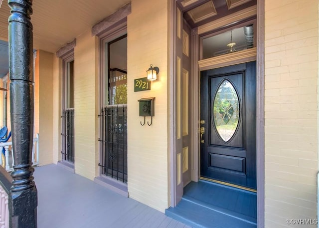 view of exterior entry with covered porch and brick siding