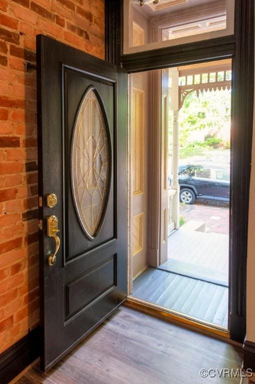 entrance foyer with wood finished floors and brick wall