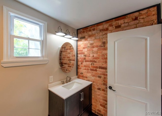 bathroom featuring brick wall and vanity