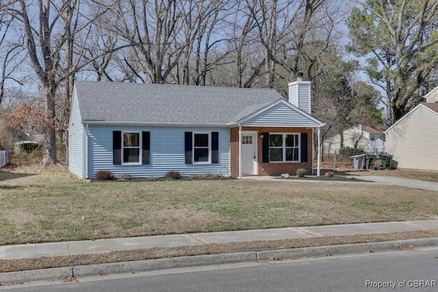 view of front of house with brick siding, a chimney, a front yard, and a shingled roof