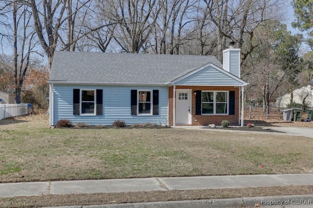 view of front facade featuring brick siding, a chimney, a front yard, and fence