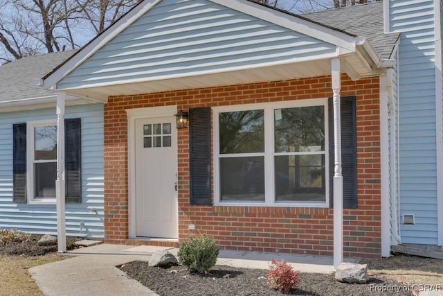 property entrance with brick siding and roof with shingles