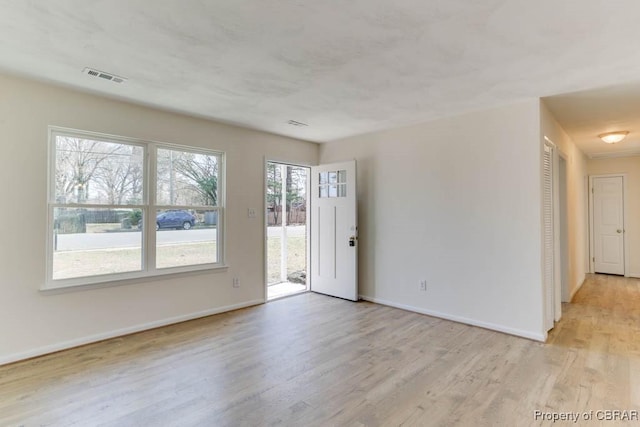 empty room featuring light wood-style flooring, baseboards, and visible vents