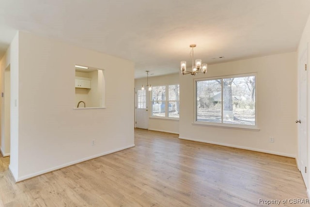 unfurnished dining area featuring a chandelier, light wood-style flooring, and baseboards