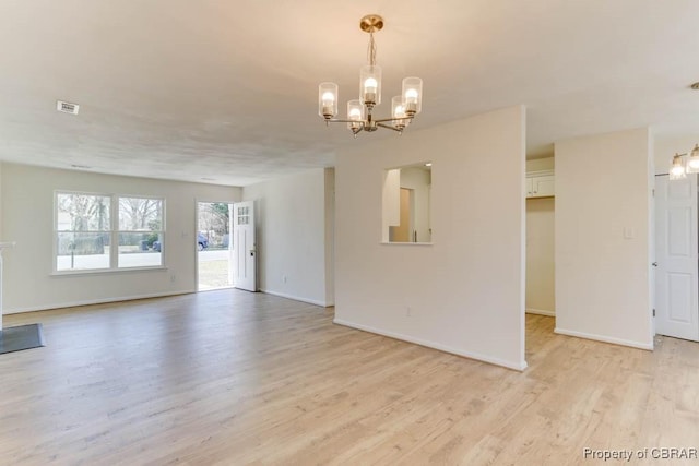 spare room featuring a notable chandelier, baseboards, visible vents, and light wood finished floors