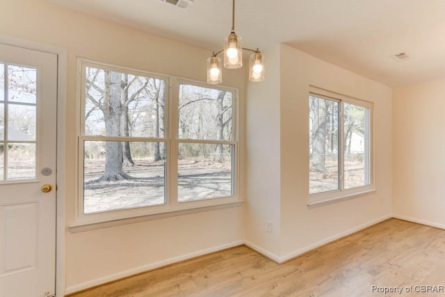 unfurnished dining area featuring light wood finished floors, visible vents, and baseboards