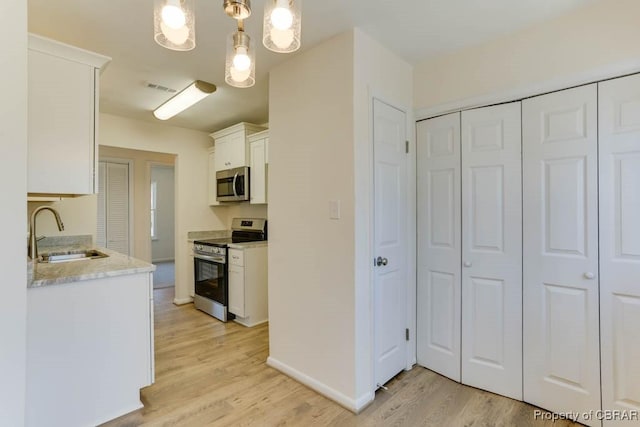 kitchen with visible vents, a sink, white cabinetry, appliances with stainless steel finishes, and light wood finished floors