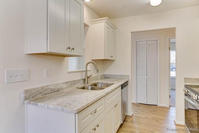 kitchen with light wood-style flooring, a sink, appliances with stainless steel finishes, white cabinets, and light stone countertops