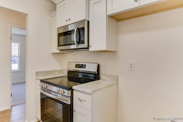 kitchen with stainless steel appliances, baseboards, white cabinets, and light countertops