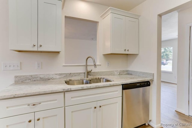 kitchen with light stone countertops, white cabinetry, a sink, light wood-style floors, and dishwasher