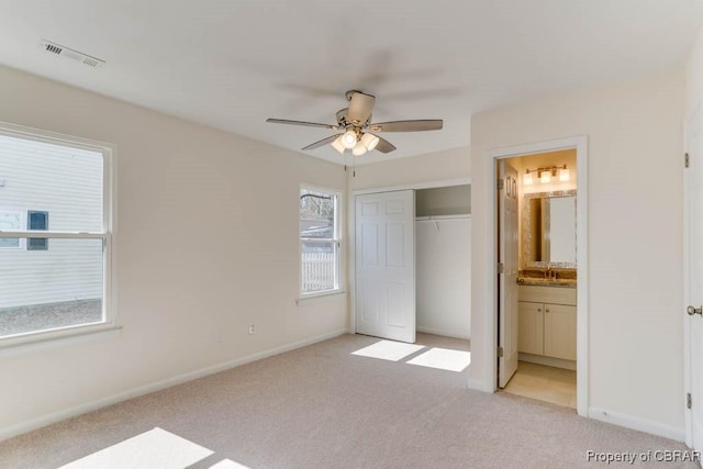 unfurnished bedroom with visible vents, baseboards, light carpet, a closet, and ensuite bath