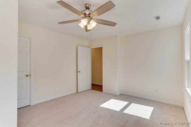 spare room with baseboards, visible vents, carpet floors, and ceiling fan