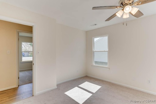 unfurnished room featuring visible vents, light carpet, baseboards, and a ceiling fan