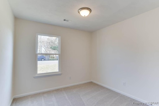 unfurnished room with visible vents, light colored carpet, and baseboards