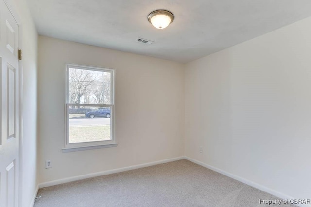 carpeted spare room with a healthy amount of sunlight, visible vents, and baseboards