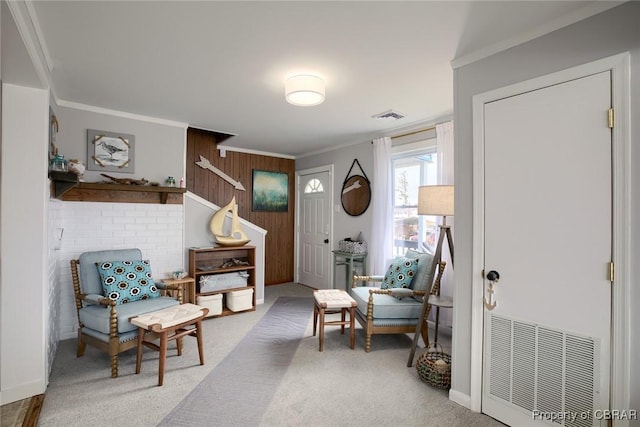 living area with visible vents, carpet floors, wood walls, and crown molding