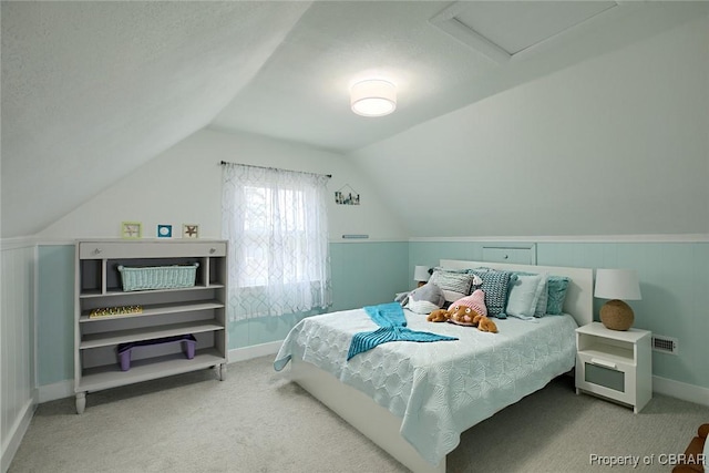 carpeted bedroom featuring baseboards, visible vents, lofted ceiling, and attic access