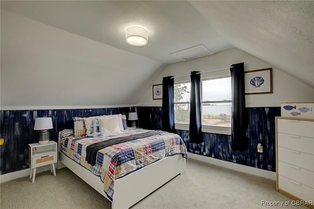 carpeted bedroom featuring lofted ceiling and wainscoting