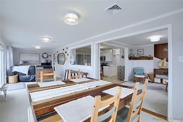 dining space featuring visible vents and ornamental molding