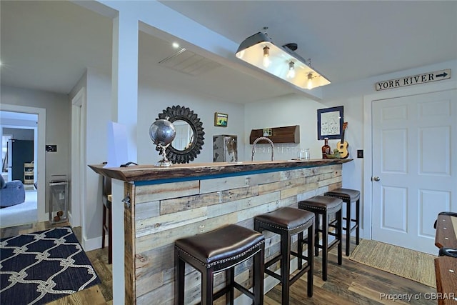 bar with bar area, wood finished floors, and freestanding refrigerator