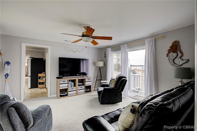 carpeted living area with baseboards and a ceiling fan