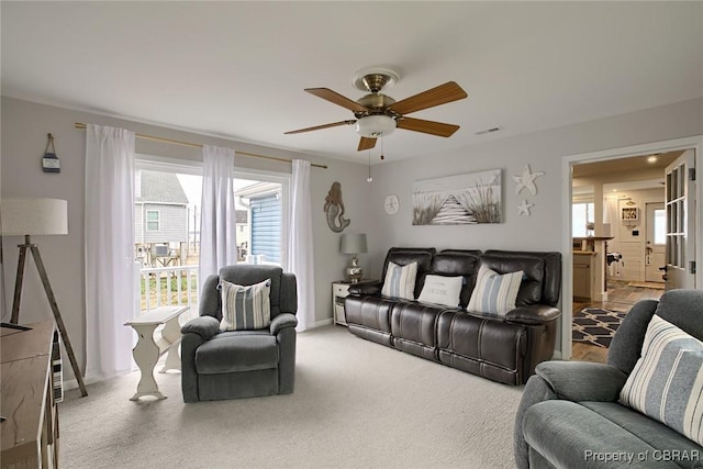 carpeted living room with visible vents, baseboards, and a ceiling fan