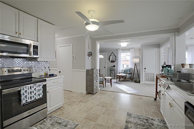 kitchen featuring a sink, appliances with stainless steel finishes, crown molding, and white cabinetry