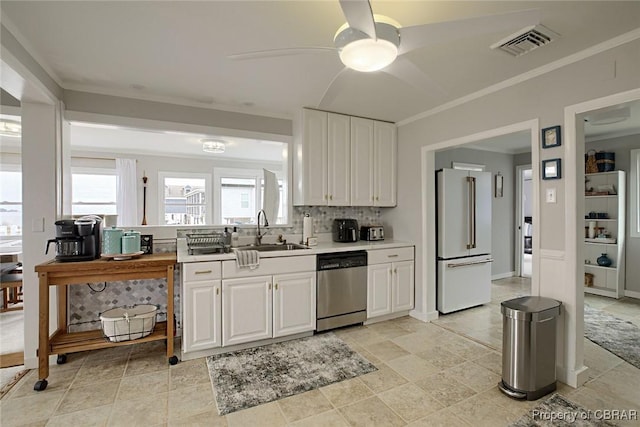 kitchen featuring visible vents, dishwasher, high end white refrigerator, a ceiling fan, and a sink