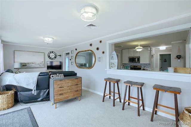 interior space with visible vents, ornamental molding, a ceiling fan, baseboards, and light colored carpet