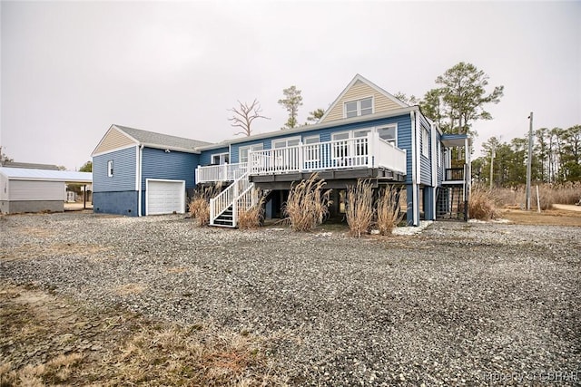 back of house with stairway, a wooden deck, and gravel driveway