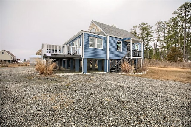 exterior space with gravel driveway, a carport, stairway, and a shingled roof