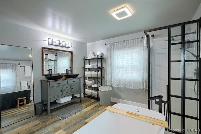 full bath featuring a shower with shower door, wood finished floors, vanity, and a freestanding tub