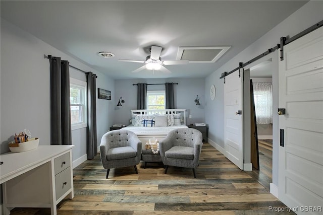 bedroom featuring visible vents, wood finished floors, a barn door, baseboards, and ceiling fan