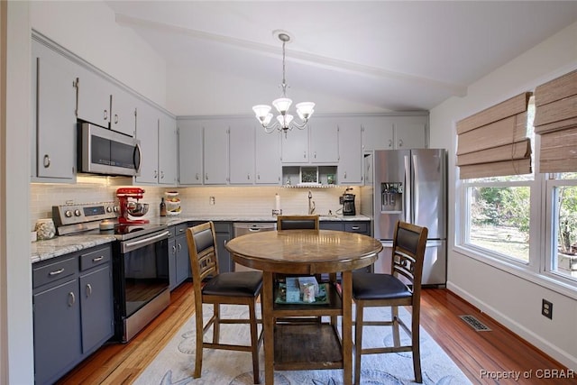 kitchen with light wood-type flooring, visible vents, appliances with stainless steel finishes, an inviting chandelier, and decorative backsplash