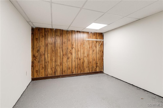 finished basement featuring a drop ceiling and wood walls