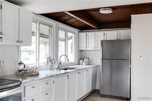 kitchen with a sink, wood ceiling, white cabinets, and freestanding refrigerator