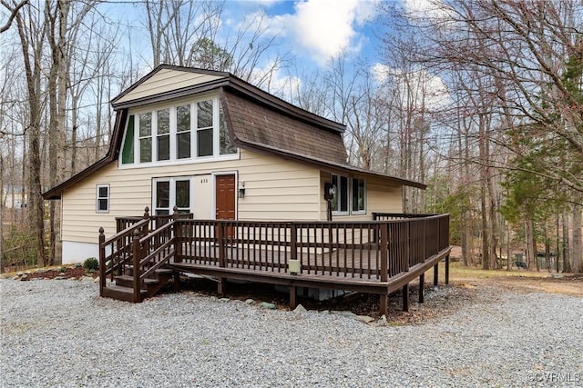 rear view of property with a deck and roof with shingles