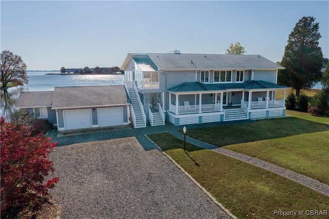 view of front of house with gravel driveway, a porch, stairs, a front yard, and a garage